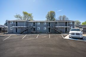 Junction City apartment for rent - A white truck is parked in a parking lot in front of a grey apartment building.