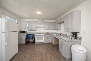 Junction City apartment for rent - A kitchen with a white refrigerator and a person in a wheelchair.