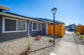 Harrisburg apartment for rent - A street lamp stands in front of a grey house with a brown fence.