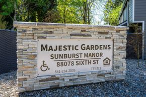 Veneta apartment for rent - Majestic Gardens Sunburst Manor sign with a stone wall and a fence.