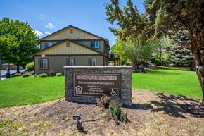 Redmond apartment for rent - A sign for Grooked River Apartments sits in front of a building.