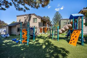 Bend apartment for rent - A playground with a slide and climbing structures in front of a house.