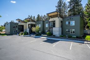 Bend apartment for rent - A parking lot in front of a building with a green roof.
