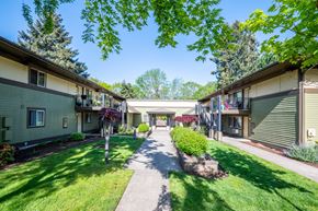 Wilsonville apartment for rent - a walkway between two buildings with a lawn and trees
