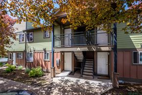 Sandy apartment for rent - front view of a green house with stairs and a balcony
