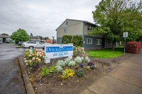 Newberg apartment for rent - a sign in front of an apartment building with flowers