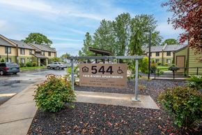 St. Helens apartment for rent - a sign in front of an apartment complex with trees and a parking lot