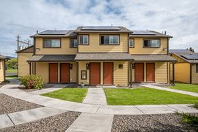 La Grande apartment for rent - the front of a yellow house with solar panels on the roof