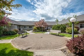 Island City apartment for rent - a circular brick patio with benches in front of a building