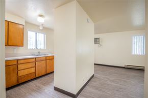 Fruitland apartment for rent - an empty living room and kitchen with wood flooring and white walls