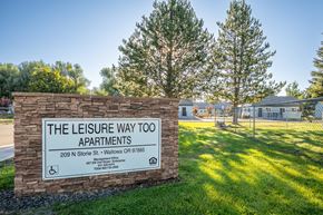 Wallowa apartment for rent - A sign for The Leisure Way Apartments stands in front of a tree.