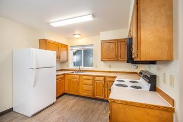 Wallowa apartment for rent - A kitchen with wooden cabinets and a white refrigerator.
