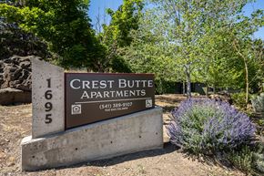 Bend apartment for rent - A sign for Crest Butte Apartments is in front of a bush with purple flowers.