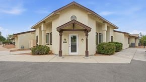 Tombstone apartment for rent - A building with a brown roof and beige walls with a white door and windows.