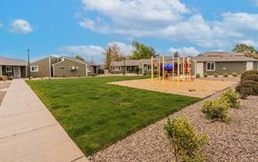White City apartment for rent - A playground with a yellow swing set is in the foreground of a residential area with houses and green grass.