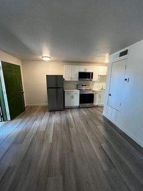 Tucson apartment for rent - A kitchen with a black fridge and white cabinets.