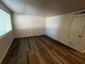 Tucson apartment for rent - A room with wooden flooring and a window with blinds.
