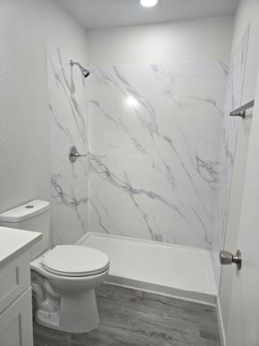 Tucson apartment for rent - A white toilet in a bathroom with marble wallpaper.
