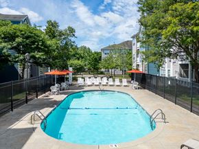 Chelmsford apartment for rent - A swimming pool surrounded by a black fence and trees at The Commons at Drum Hill