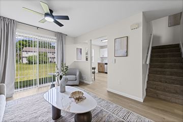 Toledo apartment for rent - A living room with a fan, a sofa, a table and a staircase.
