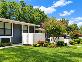 Douglasville apartment for rent - A house with a white fence and a tree with red flowers in front.