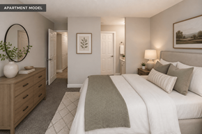 Indianapolis apartment for rent - A well-lit bedroom with a large bed and a wooden dresser.