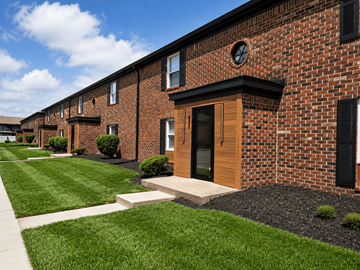Indianapolis apartment for rent - A row of red brick houses with green lawns in front.