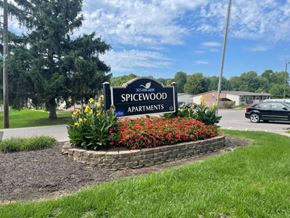 Indianapolis apartment for rent - a sign for the spiderwood apartments in a flower garden