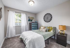 Fairfield apartment for rent - A bedroom with a bed, nightstand, and window with white curtains.