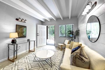 Tallahassee apartment for rent - A well-lit living room with a white couch and a round mirror on the wall.