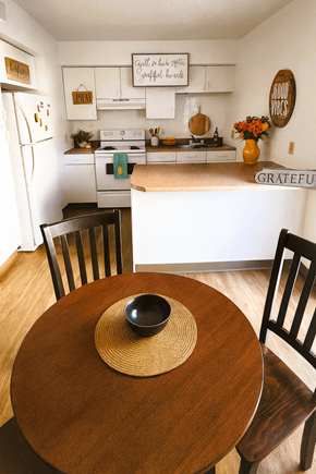 Lucasville apartment for rent - A kitchen with a table and chairs in the foreground and a fridge with magnets on it in the background.