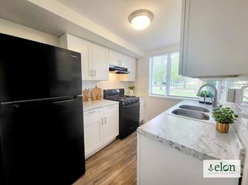 A kitchen with a black fridge, white cabinets