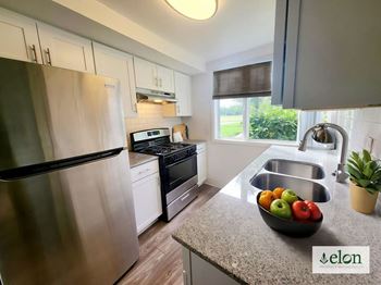 A modern kitchen with a stainless steel refrigerator and a bowl of fruit on the counter.