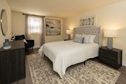 Essex apartment for rent - A bedroom with a large bed, a nightstand, and a chair at Hyde Park Apartments*, Essex, MD 21221