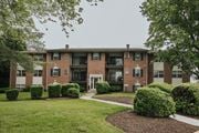 Randallstown apartment for rent - A brick building with green bushes in front at Deer Park Apartments, Randallstown, 21133