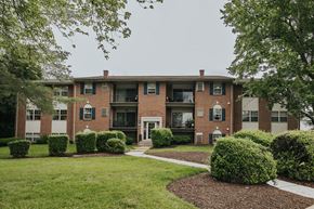 Randallstown apartment for rent - A brick building with green bushes in front at Deer Park Apartments, Randallstown, 21133