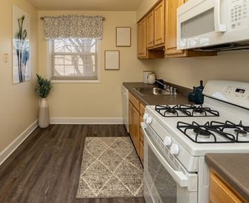 Baltimore apartment for rent - A kitchen with a white gas stove and wooden cabinets.