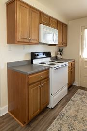 Essex apartment for rent - Wooden kitchen cabinets with white microwave and oven with gas range at Walnut Grove Townhomes*, Maryland