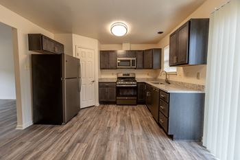 An open kitchen with dark wood cabinets and stainless steel appliances