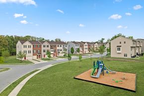 Baltimore apartment for rent - A playground with a green and blue slide in the middle of a grassy area.