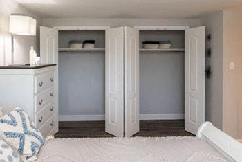 A bedroom with a bed and a dresser with a lamp on it