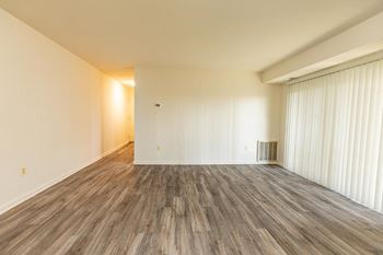 The living room and dining room of an empty house with wood flooring