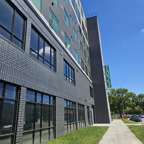 Grand Forks apartment for rent - A modern building with a grey facade and a green sign on the right side.