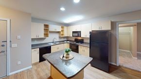 Grand Forks apartment for rent - A kitchen with a black refrigerator and a table with a vase of flowers on it.
