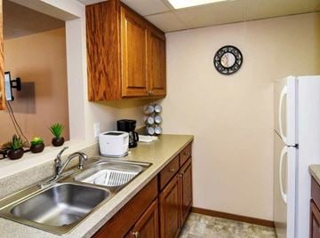 Grand Forks apartment for rent - A kitchen with a white fridge, wooden cabinets, and a clock on the wall.