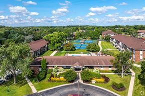 Waukesha apartment for rent - A large building with a pool in the middle of a green lawn.