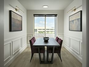 Englewood apartment for rent - A dining room with a large window, long table, and intricate paintings on the walls at The Sophia in Englewood.
