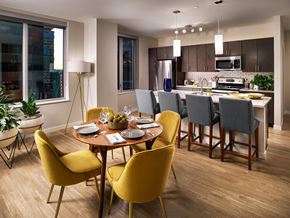 Denver apartment for rent - A model dining room and kitchen with a dining room table, island seating, and updated appliances at The Quincy in Downtown Denver.