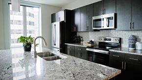 Denver apartment for rent - A model unit kitchen with modern appliances and granite countertops at The Quincy in Downtown Denver.