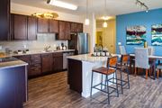 Parker apartment for rent - A kitchen and dining area with a bar and a stainless steel refrigerator at Vela Meridian Apartments in Parker.